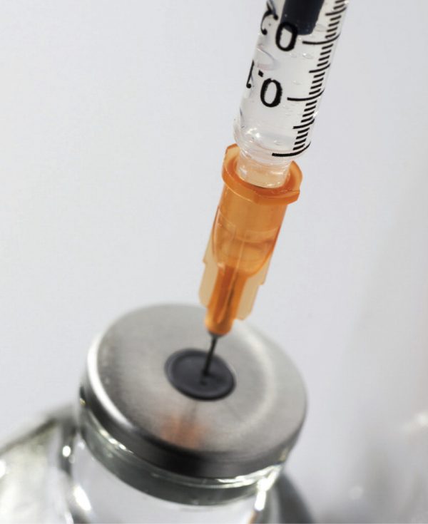 Insulin syringe puncturing a vial of compounded semaglutide