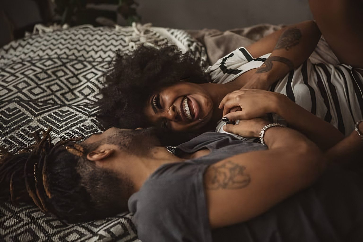 intimate black couple laughing in bed