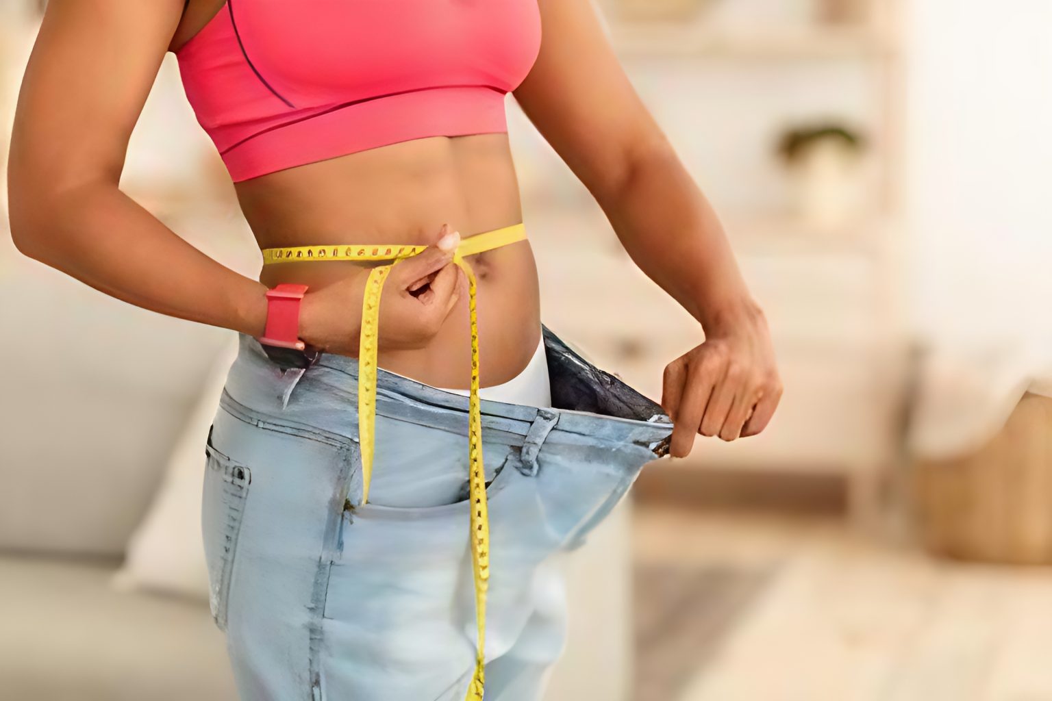 lady with a measuring tape showing her weight loss using her loose jeans